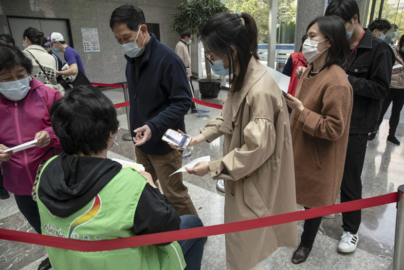 A woman shows her registration code to a volunteer (in green) while standing in line at a COVID-19 vaccination center in Shanghai, April 3, 2021. Qilai Shen/Bloomberg/People Visual