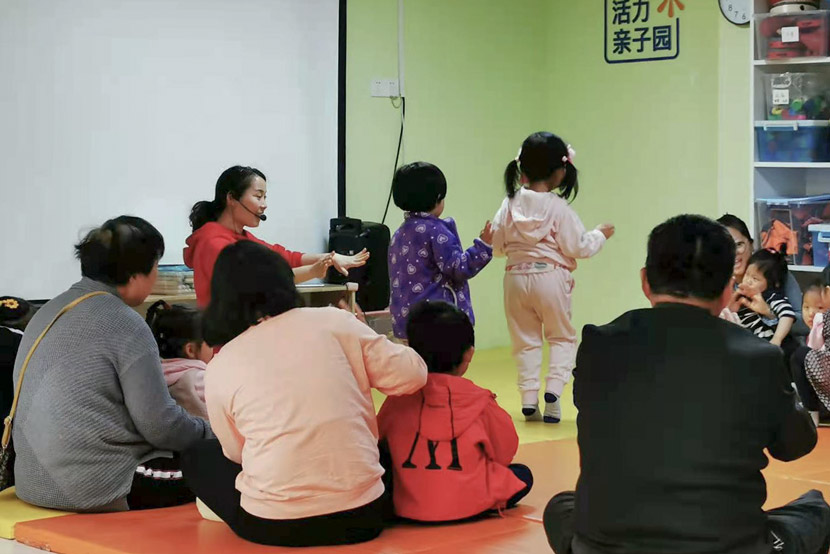 A teacher guides children and their family members at Vibrant Communities’ center in Shanghai, April 2021. Cai Yiwen/Sixth Tone