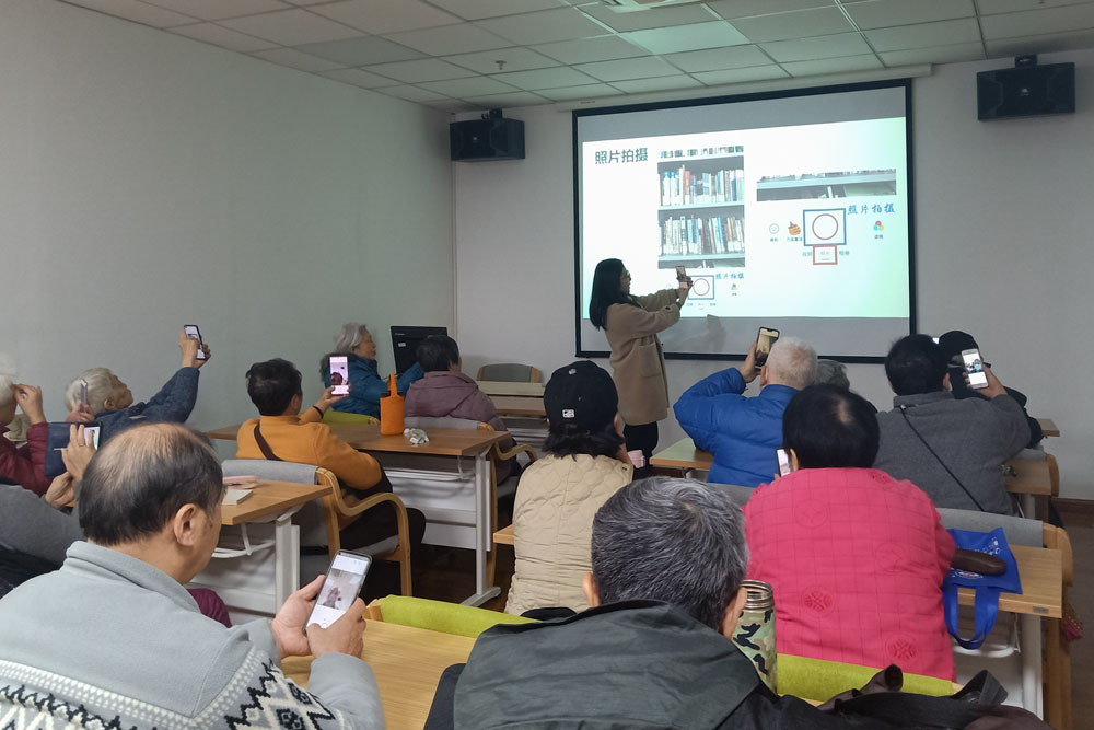 A volunteer teaches the elderly how to take photos with their smartphones, in Shanghai, Jan. 6, 2021. Courtesy of Shanghai Normal University’s “Smart Elderly” program
