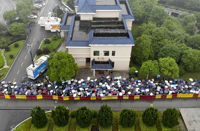 People with umbrellas wait in line in the rain to bid farewell to Yuan Longping outside the Mingyangshan Funeral Home, where his body lies, in Changsha, Hunan province, May 23, 2021. Yang Huafeng/CNS/People Visual