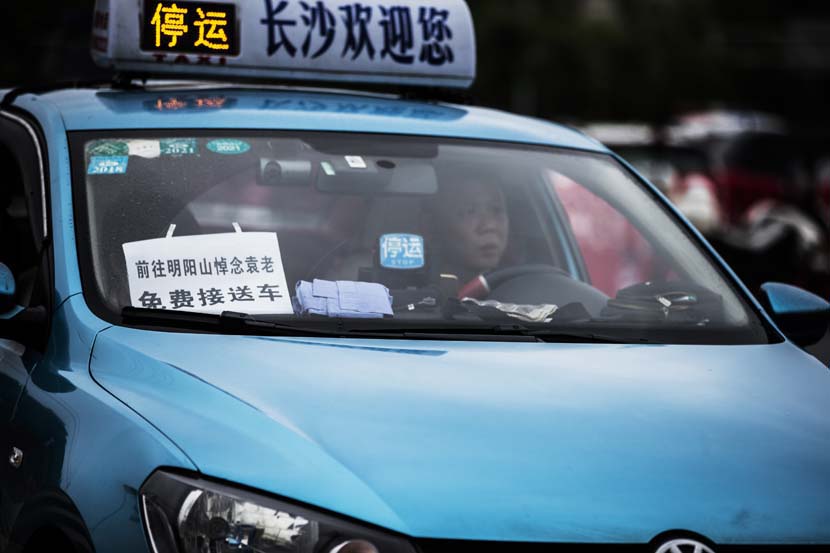 A paper sign in a taxi’s windshield reads “Free ride for those going to bid farewell to Yuan Longping at the Mingyangshan Funeral Home,” Changsha, Hunan province, May 23, 2021. People Visual
