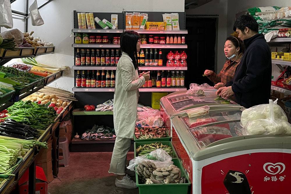 Zhang Yunhua (right) talks to a customer at her convenience store, in Wuhan, Hubei province, April 25, 2021. Wu Peiyue for Sixth Tone