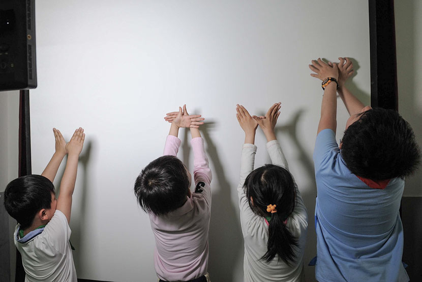 Students make shadows with their hands at an elementary school in Shanghai, May 22, 2014. Lai Xinlin for Sixth Tone