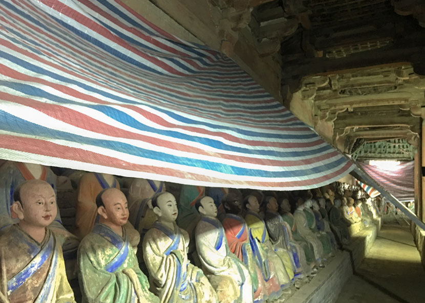 Painted sculptures are covered with a plastic sheeting at Foguang Temple in Wutai County, Shanxi Province, Aug. 28, 2017. From the official weibo of State Administration of Cultural Heritage