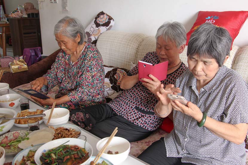 Three elderly women use WeChat to share photos of their lunch in Nanchong, Sichuan province, June 21, 2015. VCG