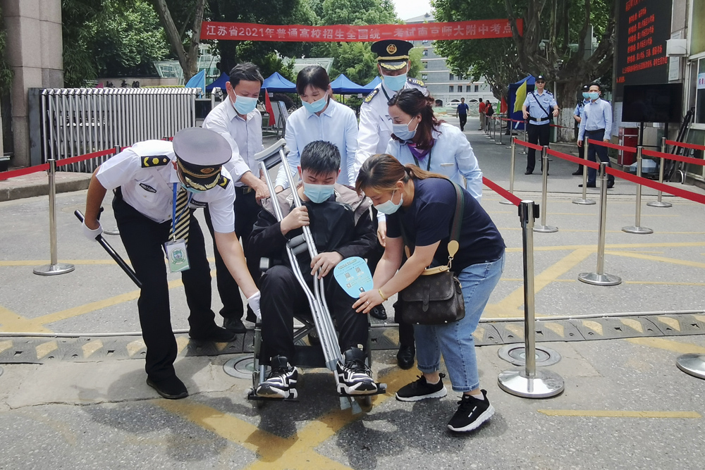 An examinee in a wheelchair leaves a testing facility with the help of site staff in Nanjing, Jiangsu province, June 7, 2021.