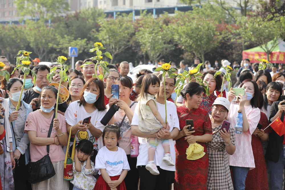 The families of test-takers hold sunflowers for good luck while waiting outside an examination site in Shandong province, June 7, 2021. People Visual