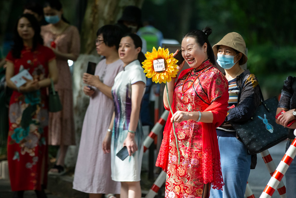 A mother of a test-taker holds a sunflower for good luck while waiting outside an examination site in Hangzhou, Zhejiang province, June 7, 2021. Chen Zhongqiu for Sixth Tone
