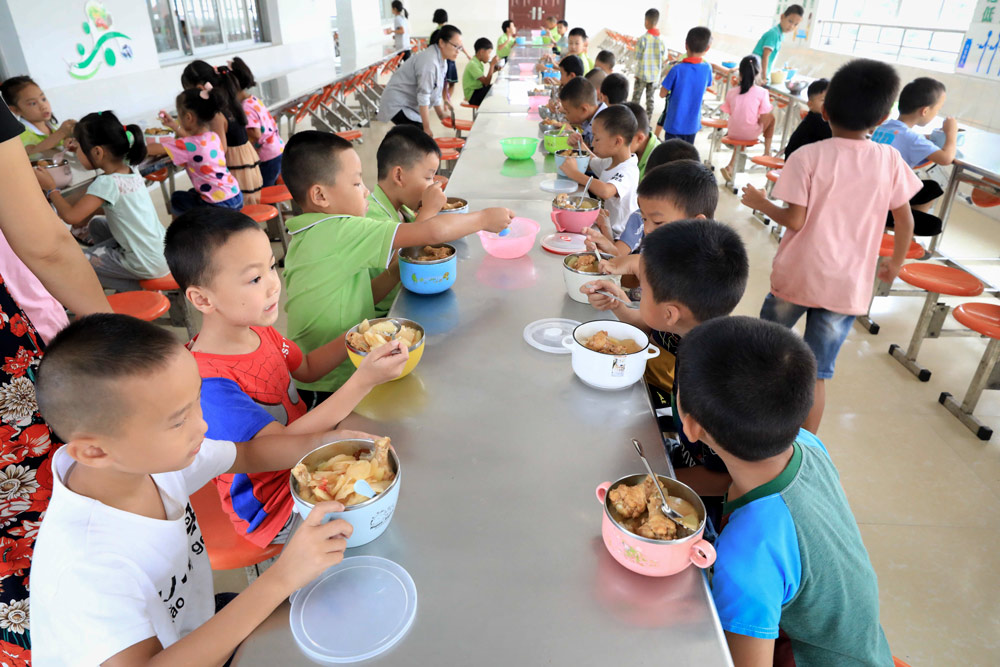 Students enjoy a free lunch at a primary school in Rong’an County, Hubei province, 2019. Tan Kaixing/People Visual