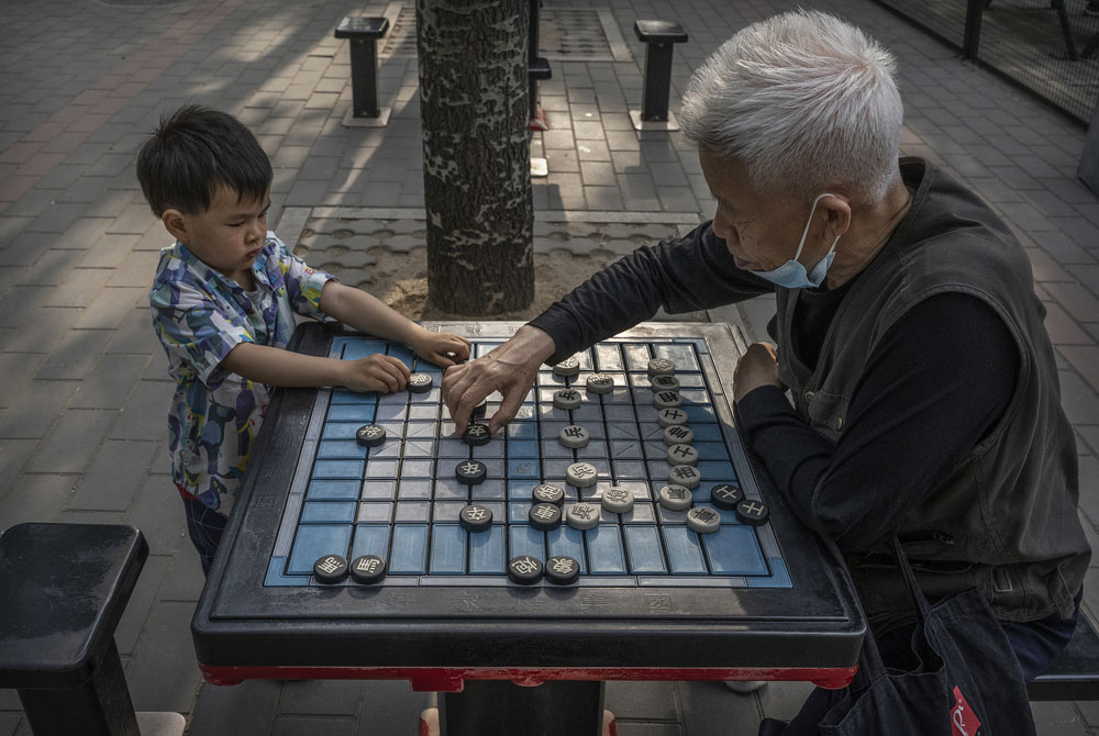 A man plays Chinese chess with his grandson at a local park in Beijing, May 12, 2021. Kevin Frayer/Getty Images/People Visual