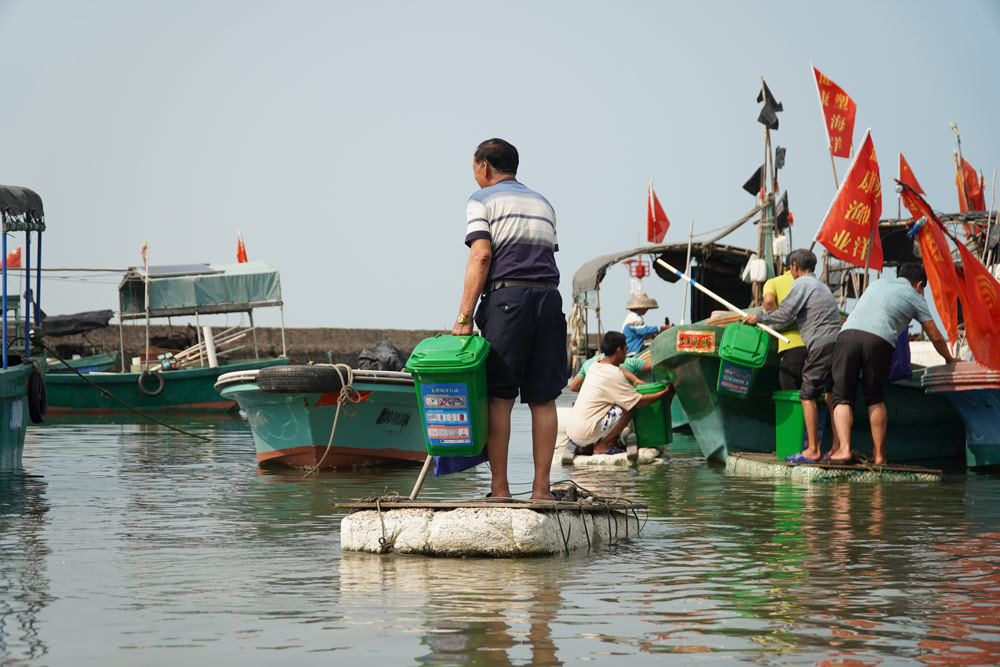 Fishermen load trash bins onto boats ahead of a trip to clean up fishery waste, Hainan province, March 15, 2021. Courtesy of Wang Songzi