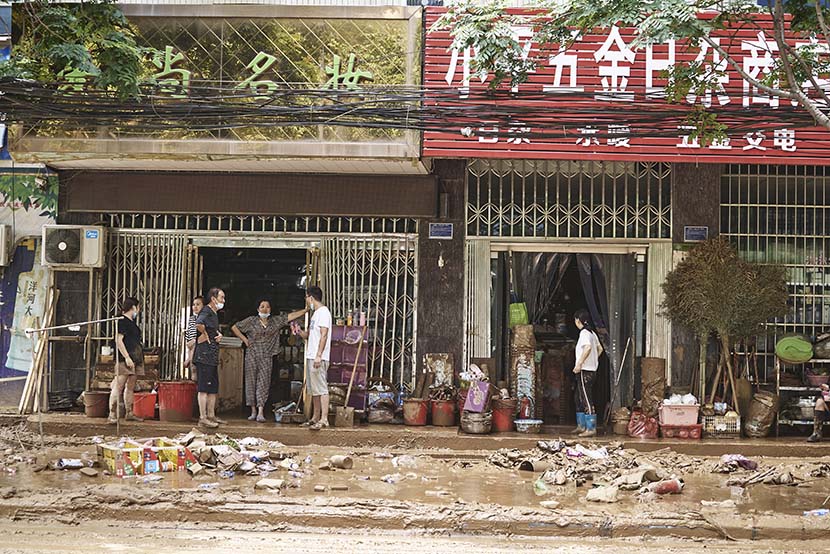 Shop owners chat outside a store in Mihe Town, July 24, 2021. Wu Huiyuan/Sixth Tone