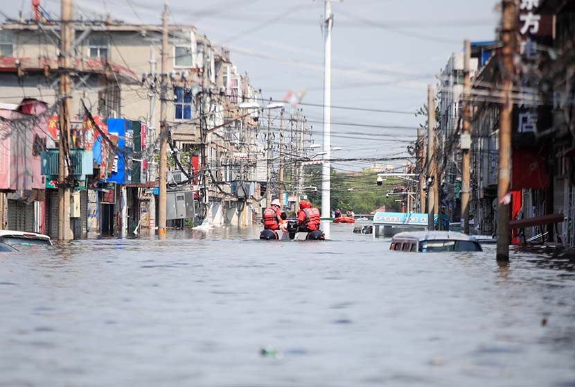 Rescue workers move local residents using an inflatable raft through a flooded street in Weihui, Henan province, July 27, 2021. People Visual