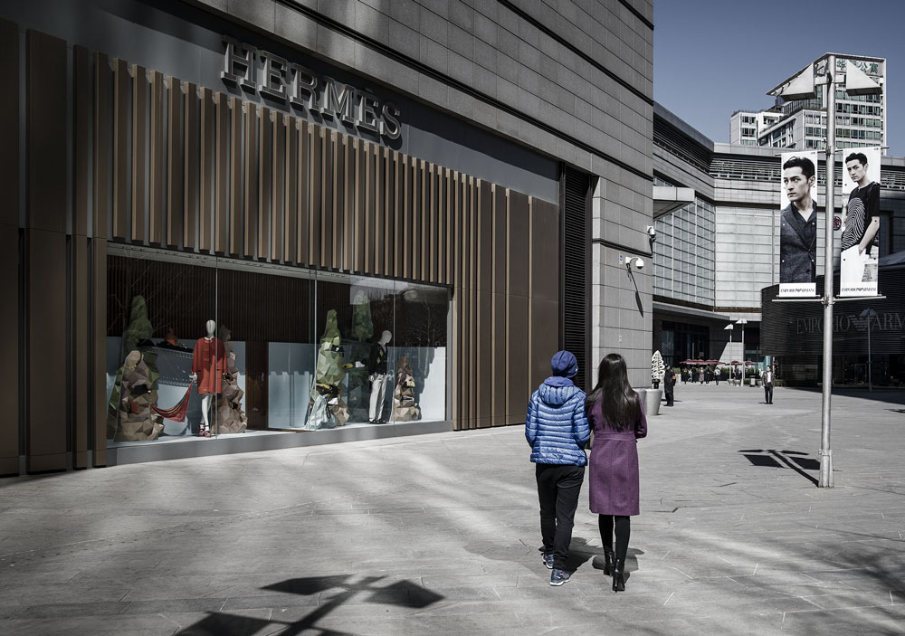 A couple walks past a Hermès store, in Beijing, March 14, 2017. Qilai Shen/Bloomberg/People Visual