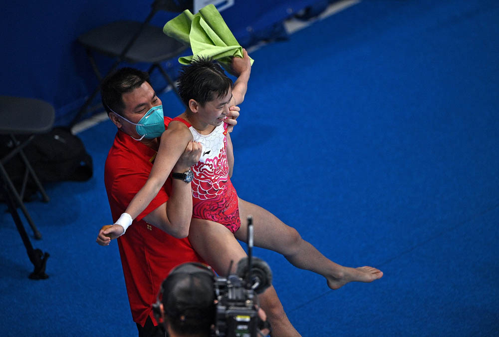 Quan Hongchan is lifted aloft by her coach after winning the women’s 10-meter platform diving event, Aug. 5, 2021. Oli Scarff/AFP via People Visual
