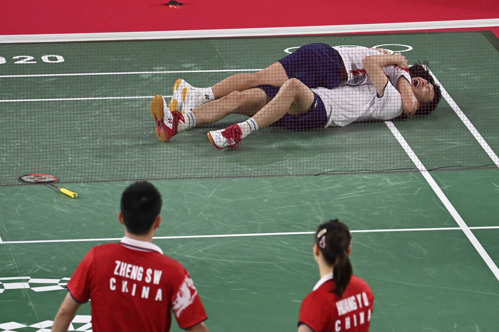 Huang Dongping (left) and Wang Yilü celebrate their win in the mixed doubles badminton final as Zheng Siwei (bottom left) and Huang Yaqiong look on, July 30, 2021. Alexander Nemenov/AFP via People Visual