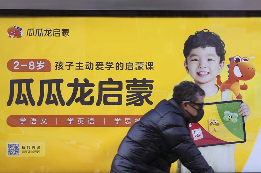 A man passes by an advertisement for Guagualong in Beijing, Dec. 21, 2021. People Visual