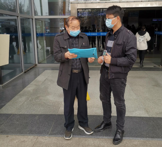 Lu (right) talks to his client outside of a hospital. Courtesy of Lu