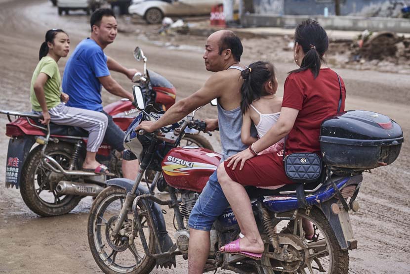 Villagers ride motorcycles on a muddy road in Mihe Town, Henan province, July 23, 2021. Wu Huiyuan/Sixth Tone