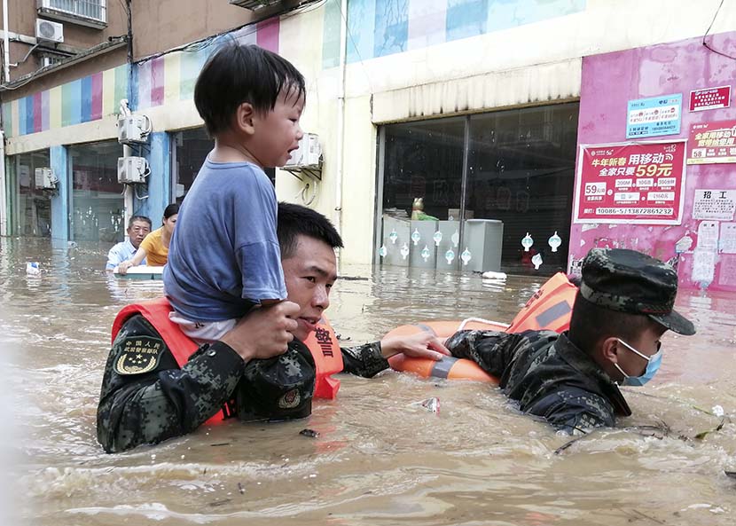 Rescue workers carry a child through flood waters in Suizhou, Hubei province, Aug. 12, 2021. People Visual
