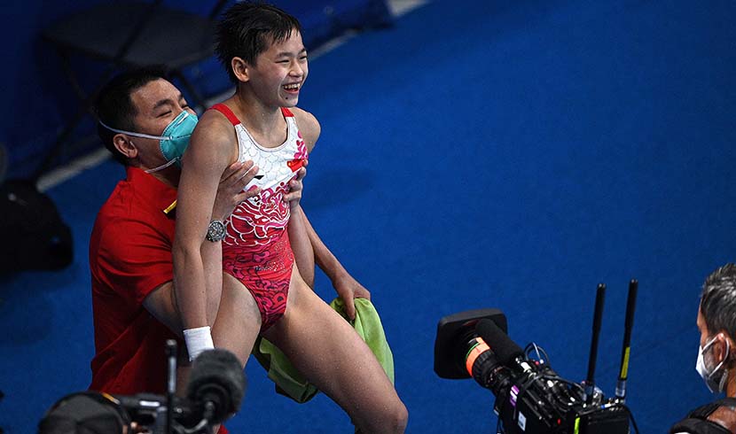 Quan Hongchan is lifted aloft by a coach after seeing the score and winning the women's 10m platform diving final event during the Tokyo 2020 Olympic Games at the Tokyo Aquatics Centre in Tokyo, Japan, Aug. 5, 2021. Oli Scarff/AFP/People Visual