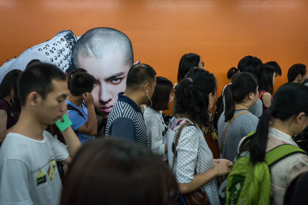 Passengers walk past an ad featuring Kris Wu at a subway station in Beijing, 2016. People Visual