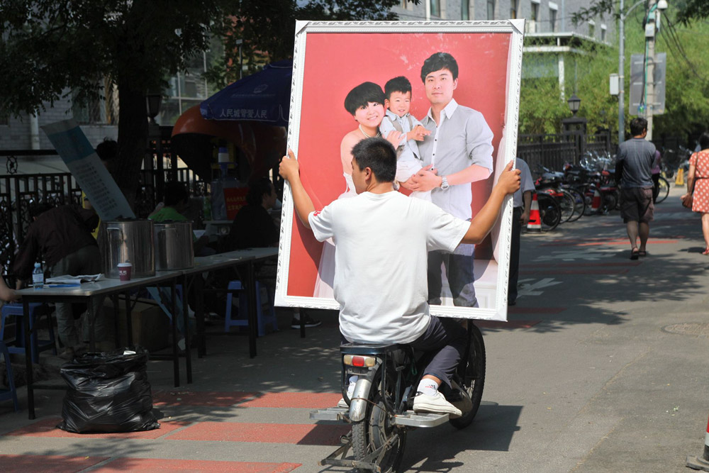 A man helps transport a large family photo in Beijing, 2012. Zhang Jusheng/People Visual