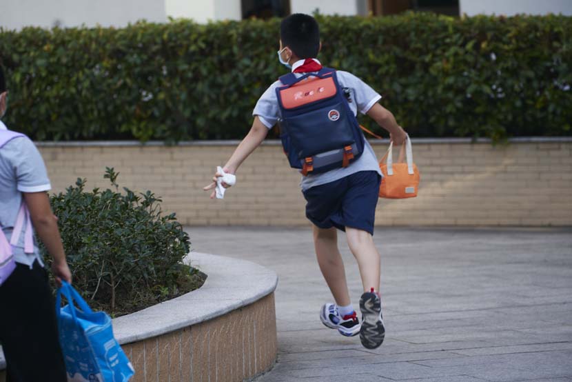 A boy runs to the entrance of the Primary School Affiliated to Shanghai University, Sept. 1, 2021. Wu Huiyuan/Sixth Tone