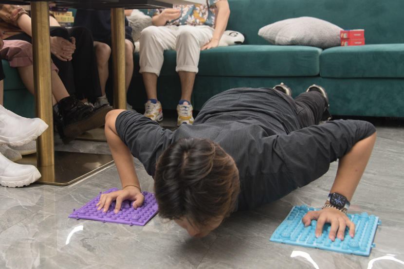 A butler does push-ups after losing a game at the café, Shanghai, August 2021. Xie Anran/Sixth Tone