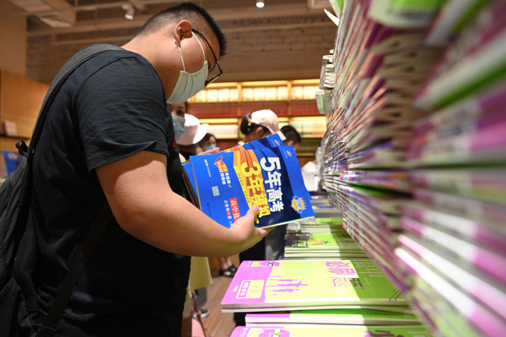 A student flips through copies of “Five Years of College Entrance Exams and Three Years of Mock Tests” at a bookstore in Hefei, Anhui province, Sept. 5, 2020. IC