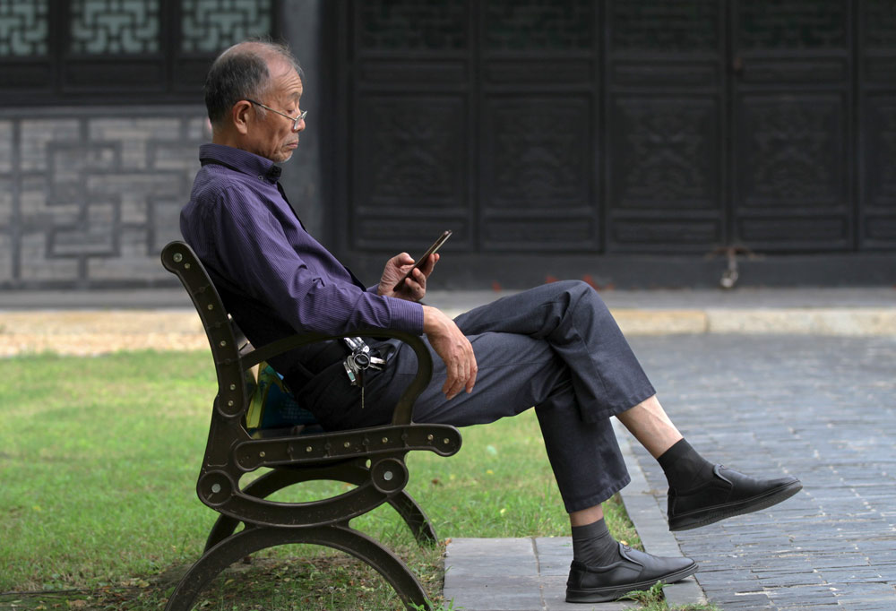 A man looks at his mobile phone in a park in Huai’an, Jiangsu province, Sept. 4, 2021. Zhou Changguo/IC