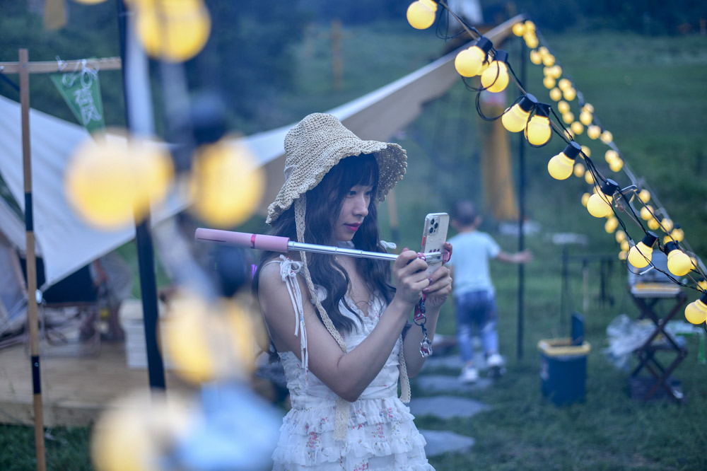 A woman checks her photos at a camping site in Jinan, Shandong province, July 2021. Yi Chu/IC