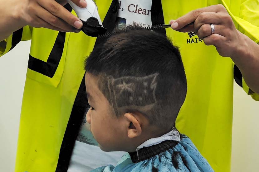 A boy gets a pattern of China’s national flag on his head at a salon in Wuhan, Hubei province, Sept. 30, 2021. People Visual