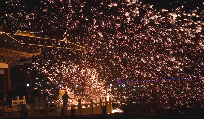 A man throws molten iron to create firework-like impression at a tourist site in Lianyungang, Jiangsu province, Oct. 1, 2021. People Visual