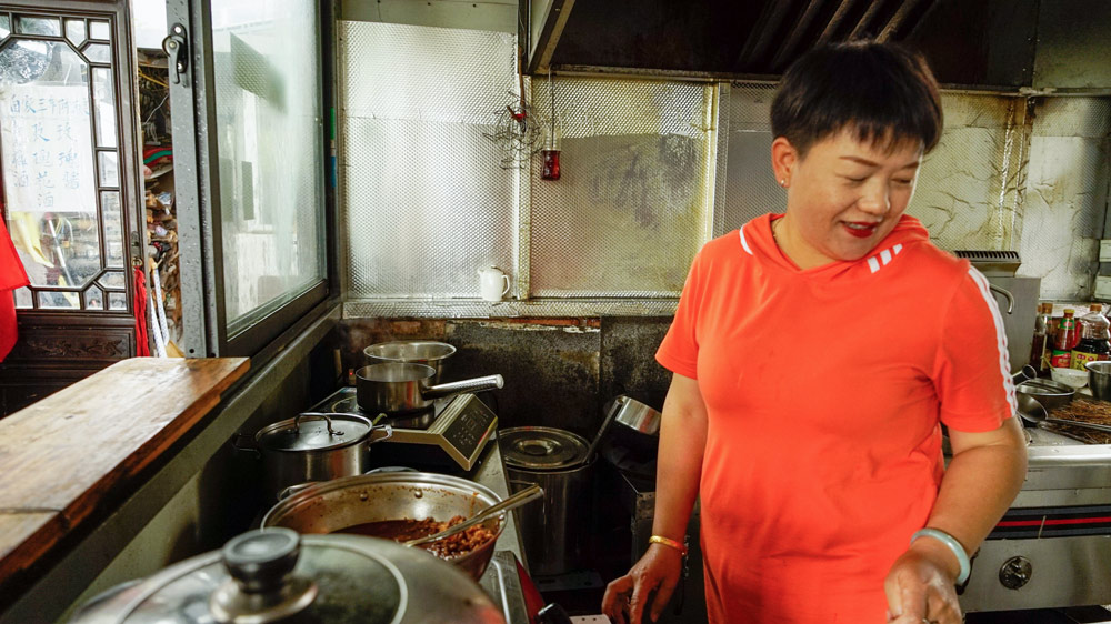 Yang, a local restaurant owner, prepares a meal in Dali, Yunnan province, Oct. 6, 2021. She described the convertible rental business as a microcosm of Dali's tourism development. Jiang Yaling/Sixth Tone