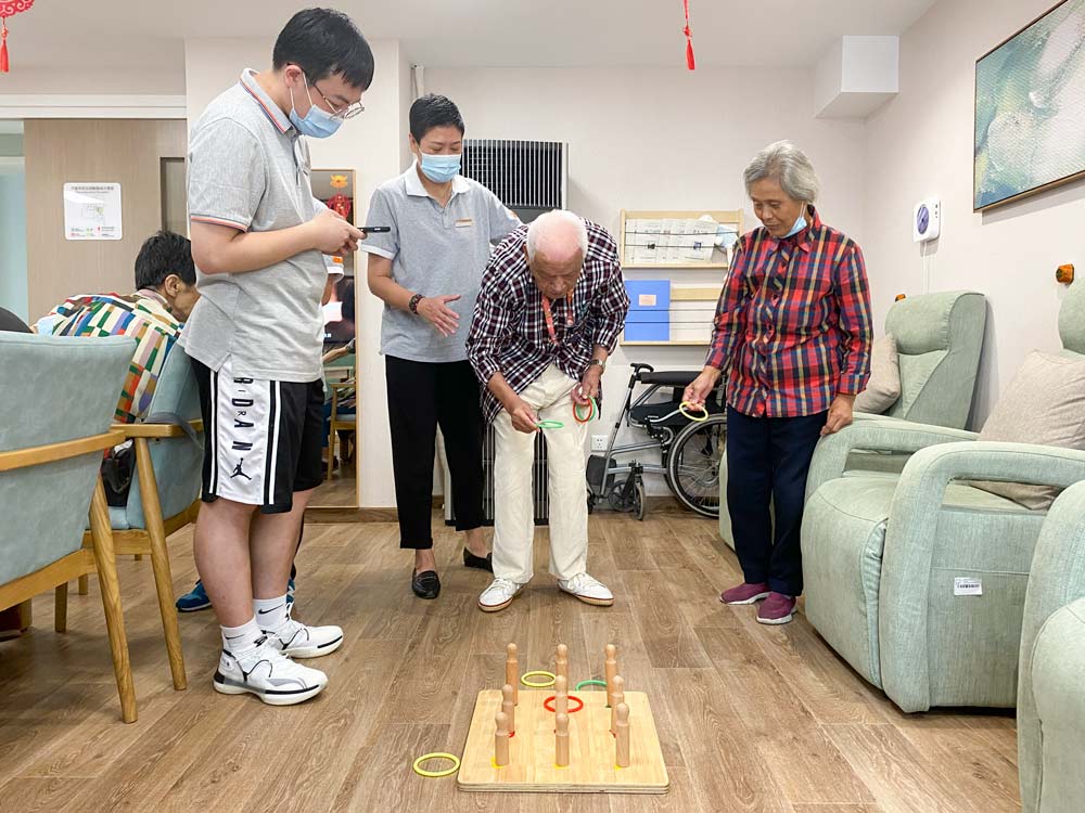 Zhong Zhixiang (center) plays the hoop toss at Huayang Integrated Elder Care Center, Shanghai, Aug. 20, 2021. Fan Yiying/Sixth Tone