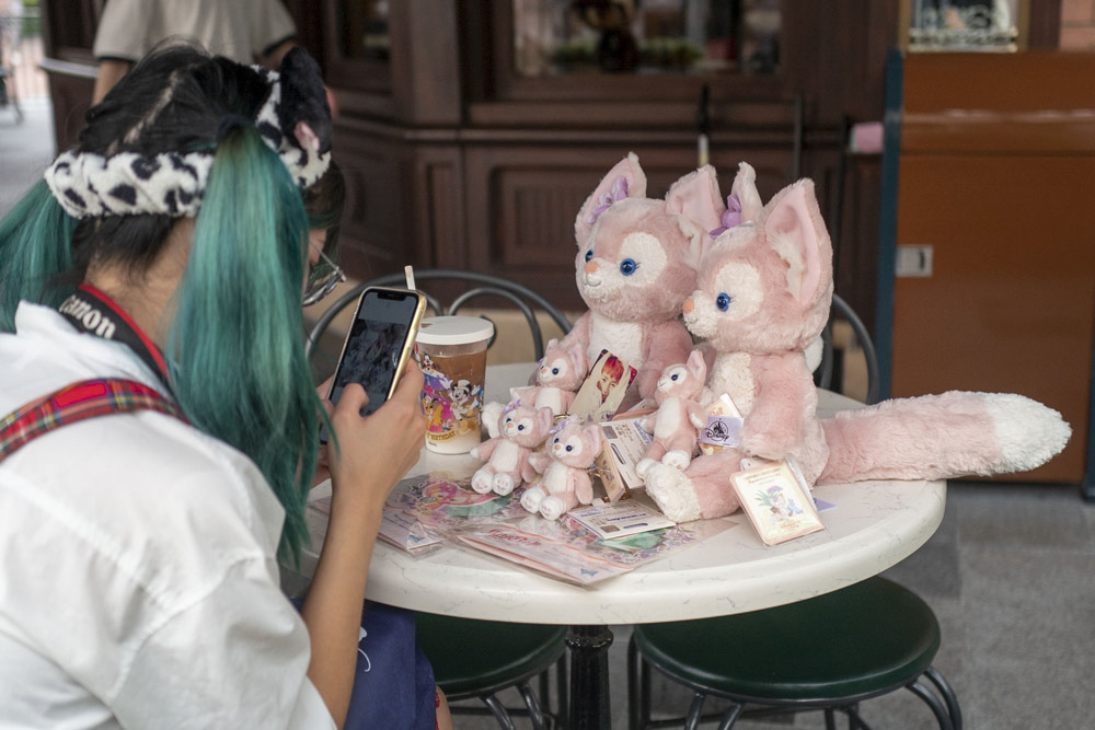 A young woman takes photos of LinaBell toy dolls at Shanghai Disney Resort, Sept. 29, 2021. IC