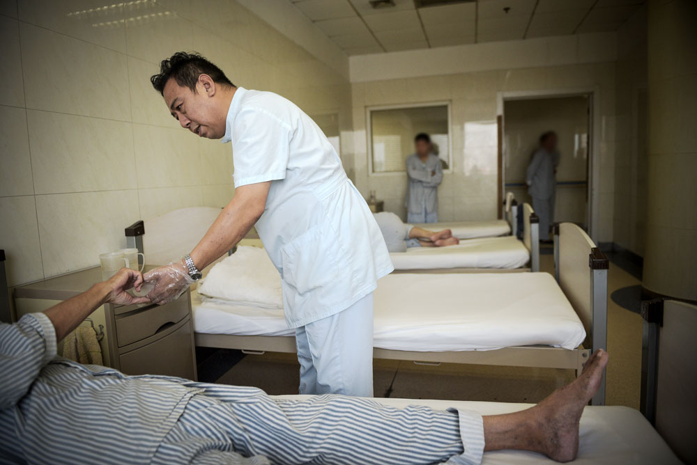 A medical worker checks on a patient at a psychiatric ward in Tianjin, July 2018. You Sihao/Tecent/People Visual