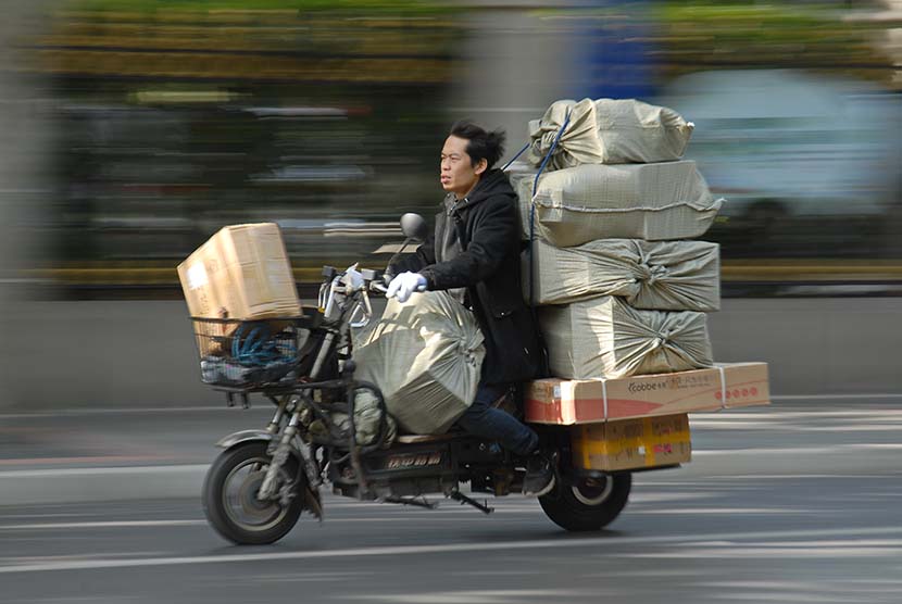 A deliverman rides a motobilke with loads of packages in Shanghai, Nov. 19, 2019. People Visual