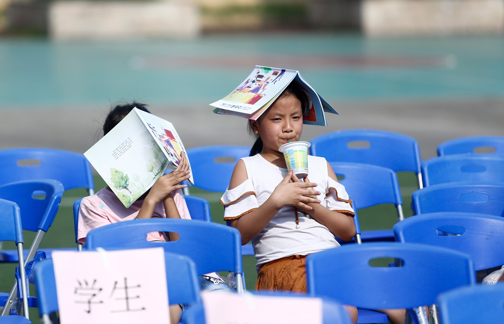 Primary school students use books to shade themselves in Guangzhou, Guangdong province, 2018. He Yushuai/Southern Metropolis Daily/People Visual