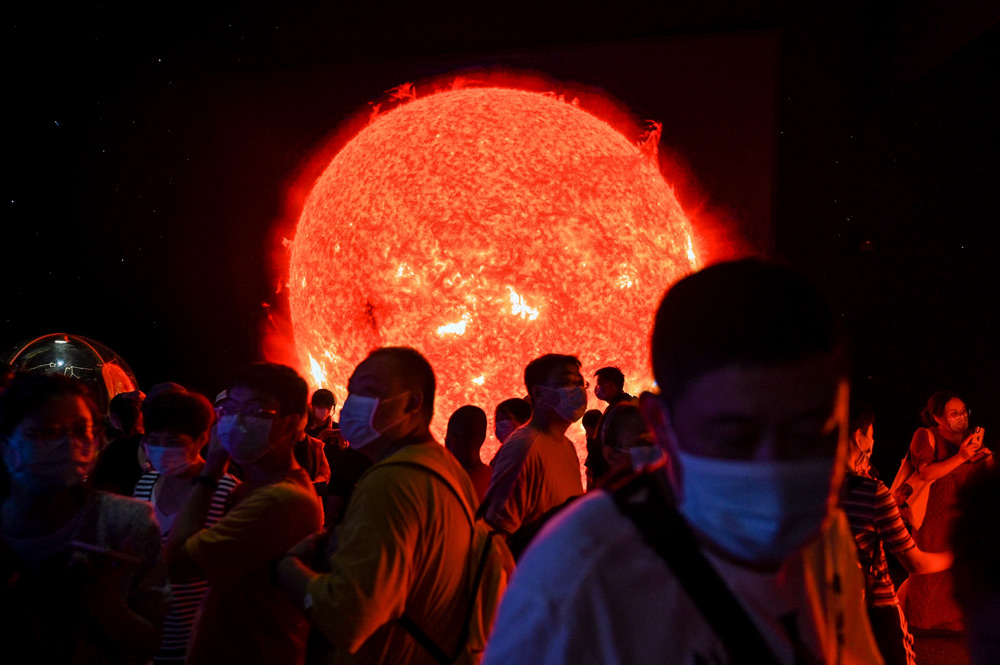 Visitors stand in front of a digital recreation of the sun at the newly opened Shanghai Planetarium, July 30, 2021. Hector Retamal/AFP