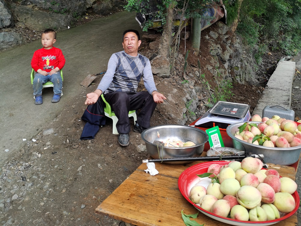 A villager and his son sell peaches in Yangdeng Town, Guizhou province, May 2021. Courtesy of Lou Jin