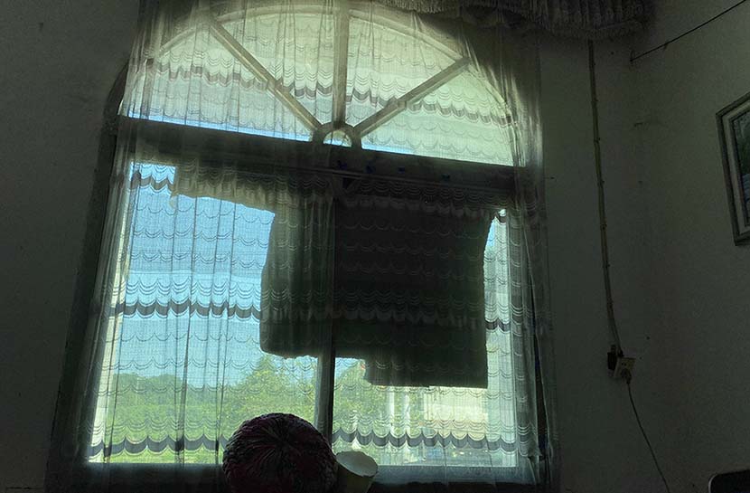 The window of Li Xiaozhong’s living room is patched with cardboard to keep excess light out. Chen Canjie for Sixth Tone