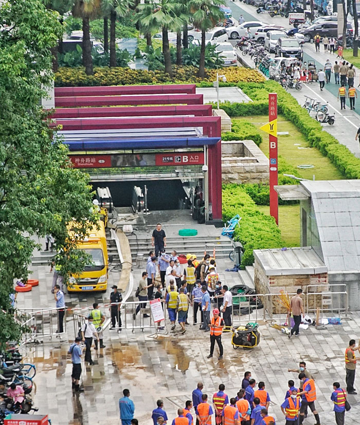 Workers stand outside a flooded subway station, in Guangzhou, Guangdong province, July 30, 2021. Southern Visual/People Visual