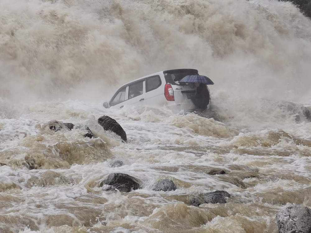 A van driver waits for rescue during flooding in Yichang, Hubei province, April 7, 2021. Wu Lingjian/People Visual