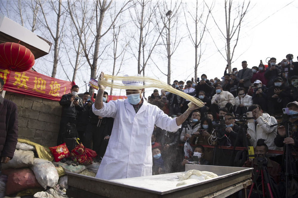 Cheng Yunfu makes noodles as livestreamers crowd around him at a village in Linyi, Shandong province, March 9, 2021. IC