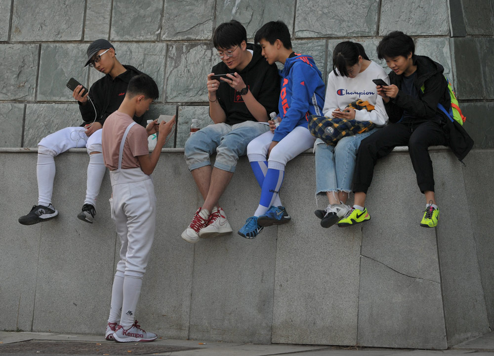 Young people play with their cell phones on a street in Yangzhou, Jiangsu province, 2019. People Visual