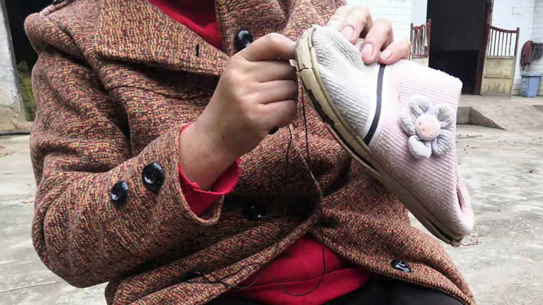 Zhang’s wife mends a slipper outside their house in Gantian Town, Hunan province, November 2021. Ming Que/The Paper