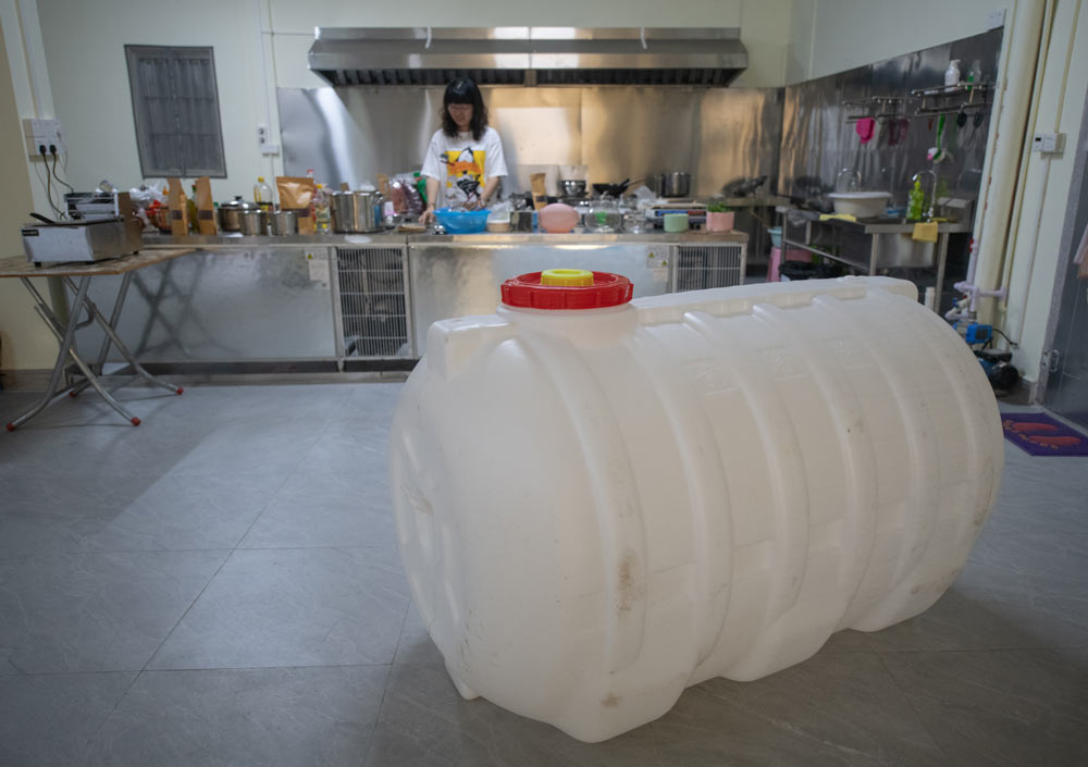 A woman stands in her kitchen, which she has fitted with a large storage tank to cope with water shortages, in Shantou, Guangdong province, April 8, 2021. Southern Visual/People Visual