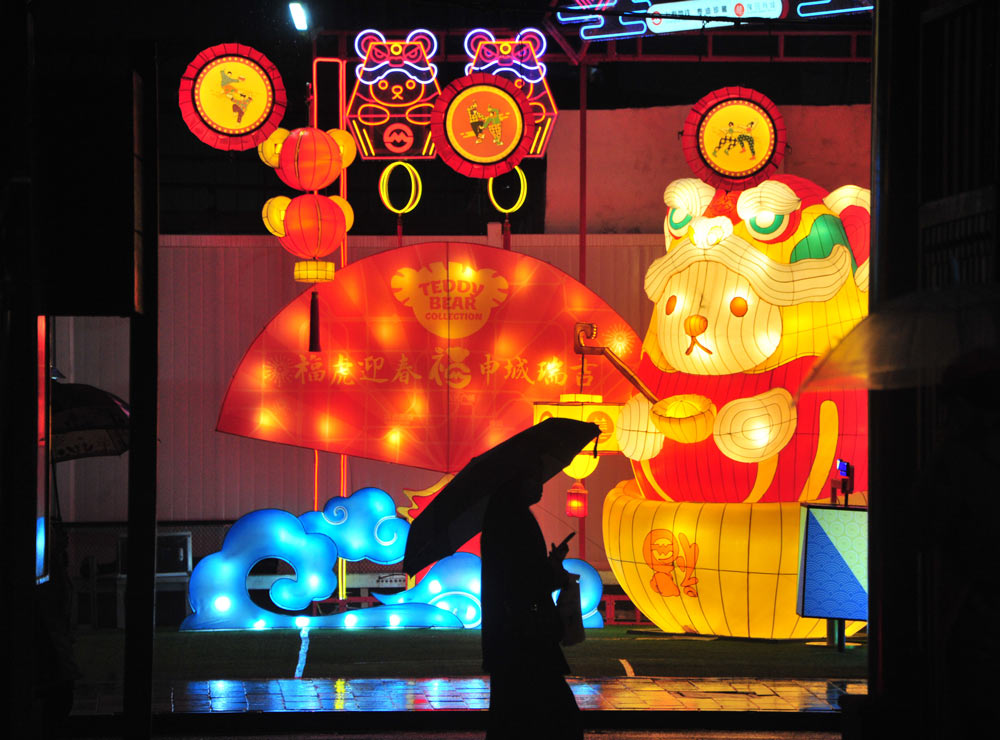 A visitor looks at the lanterns on display at Yu Garden, Shanghai, Jan. 23, 2022. People Visual)